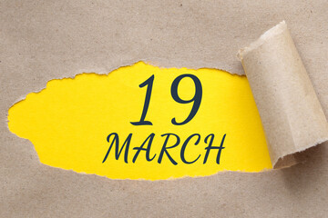 march 19. 19th day of the month, calendar date. Hole in paper with edges torn off. Yellow background is visible through ragged hole.Spring month, day of the year concept