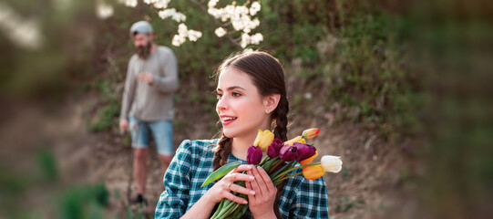 Spring woman face for banner. Young woman entrepreneur working in flower garden. Young woman holding tulips in the garden.