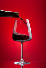 Red wine pouring from bottle into glass