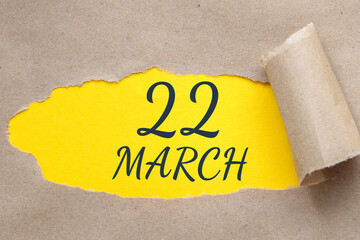 march 22. 22th day of the month, calendar date. Hole in paper with edges torn off. Yellow background is visible through ragged hole.Spring month, day of the year concept