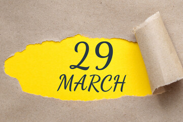 march 29. 29th day of the month, calendar date. Hole in paper with edges torn off. Yellow background is visible through ragged hole.Spring month, day of the year concept