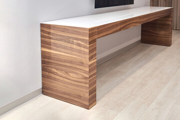 Contemporary TV console in minimalist style of walnut wood and white glass table top in office...