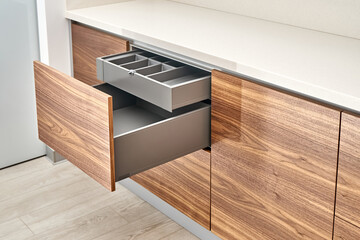 Open drawers of dark grey color with cutlery tray in contemporary kitchen of walnut wood and gray...