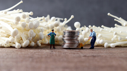 Enoki mushrooms and miniature people. Miniature people and piles of coins with business concepts.
