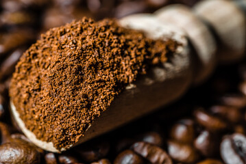 Ground coffe in spoon on coffee bean background