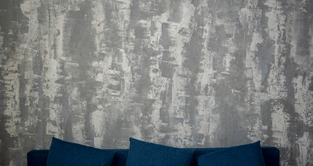 Blurry creative wall and blue sofa. Rough textured surface with vertical abstract lines and shapes. No selective focus, defocused background.