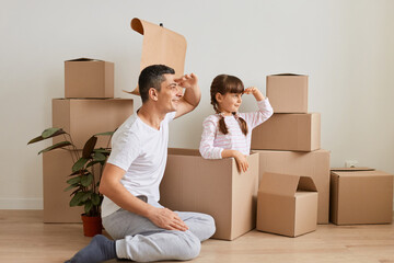 Indoor shot of little girl making ship with flag during relocation and playing sailor with dad,...