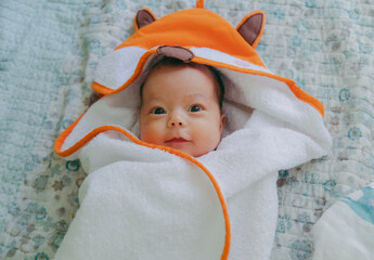 Closeup of newborn baby girl wrapped into hooded baby towel