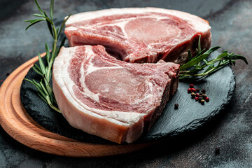 Organic Pork meat chop set with spices and rosemary and red pepper on black table. top view