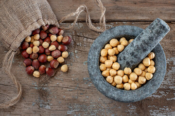Many hazelnuts in the stone mortar and sack bag. Dried nuts concept. 