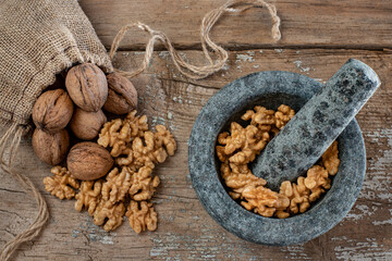 Many walnuts in the stone mortar and sack bag. Dried nuts concept. 