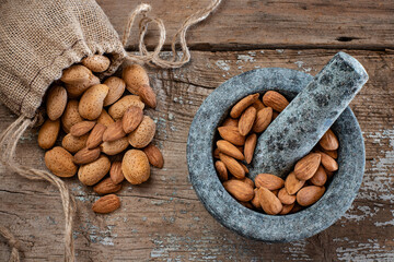 Many almonds in the stone mortar and sack bag. Dried nuts concept. 