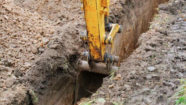 Mini excavator digs a trench to lay pipes. excavator bucket close up.
