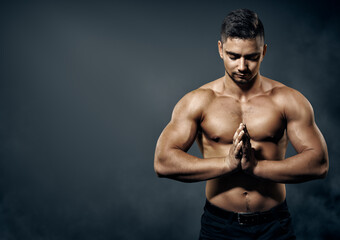 Fototapeta na wymiar Bodybuilder Man. Athlete showing Muscles of Strong Body and Hands over Dark Gray Background. Topless Men doing Meditation Yoga Exercise. Sportsman Health Concept