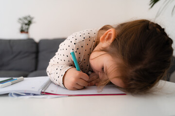 Portrait of cute preschooler child girl drawing with pencils at home while sitting in front of the...