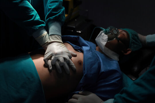 Closeup image of professional concentrated surgical team performing CPR on patient in hospital operating room or emergency room. Surgery concept