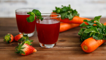 Closeup studio shot two glasses of freshly blended squeezed decorated with strawberry and carrot healthy diet vegan drink fresh fruit vegetable place on wooden table for advertisement with copy space