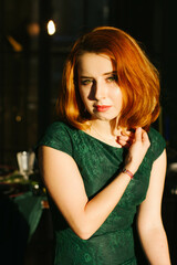 Obraz na płótnie Canvas red-haired woman in green dress posing