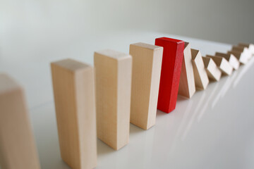 One red wooden block stop other ones from falling like dominoes, domino effect