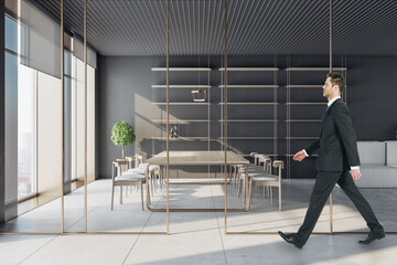 Businessman walking in modern conference room interior with window and city view, glass partition and daylight. Workplace concept.