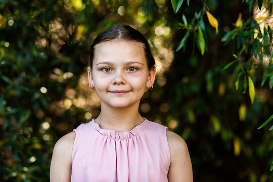 Portrait of young ten year old girl with natural green bokeh background