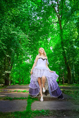 Fototapeta premium Portrait of beautiful pretty bride in an unusual wedding dress walking and standing alone in the green park in a summer or spring day