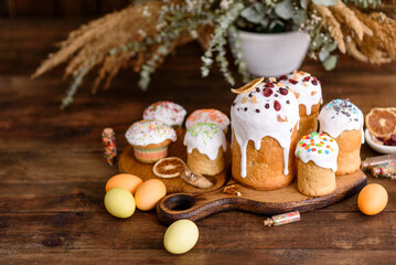 Easter holiday concept. Easter cakes (orthodox kulich), willow, painted eggs and candle on rustic wooden table