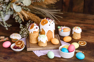 Easter holiday concept. Easter cakes (orthodox kulich), willow, painted eggs and candle on rustic wooden table