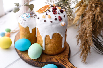 Festive cakes with white glaze, nuts and raisins with Easter eggs on the festive table
