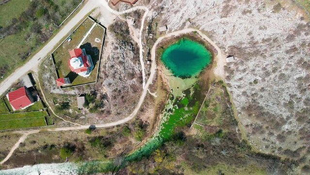 A cinematic, rotating aerial shot of Izvor Cetine, a turquoise blue natural karst spring called The Eye of The Earth that is the source of the Cetina river in Croatia, and a famous national monument.