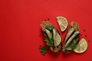 Tasty sandwiches with sprats on red background