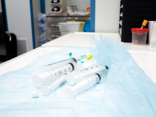 Several large syringes close-up on a crumpled blue medical diaper in a hospital. Medical equipment.