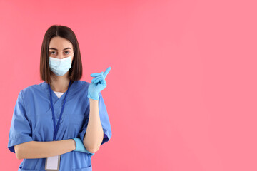 Female trainee nurse in gloves and mask on pink background