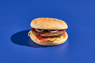 Beef burger blue background with hard shadow. American junk food minimal style. Hamburger trendy...