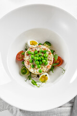 Original russian potato salad with green peas and mayonnaise. Russian christmas menu. Olivier salad with boiled potatoes, carrots, eggs, peas and meat with mayo dressing.  Traditional New year dish.