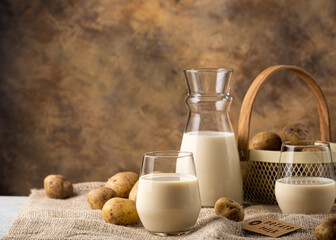 Vegan plant based milk in two transparent glasses and decanter. Alternative potato milk and potato...