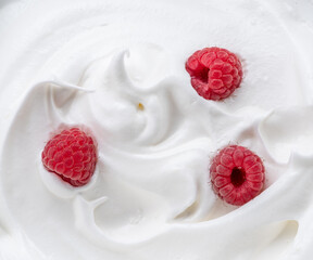 Fresh raspberries in the yoghurt or cream. Top view.