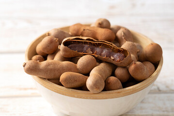 Fresh Tamarind fruits (Tamarindus indica, Indian date) Sweet ripe tamarinds on white wood rustic background. close-up	
