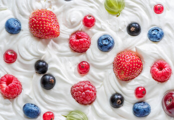 Mix of fresh berries in the yoghurt or cream. Top view.