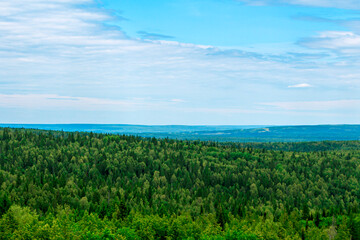 Fototapeta na wymiar Natural beautiful landscape. View from mountain on forest valleys against blue cloudy sky. National park, layered Hills. Lookout point. Deciduous and coniferous