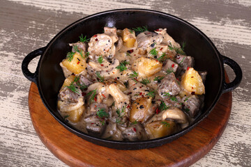 A dish of potatoes and mushrooms on a wooden table in a frying pan