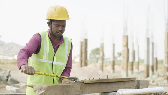 Indian construction worker with hard hat bending steel rod at workplace - concept of hard worker, daily wagers lifestyle and blue coller jobs,