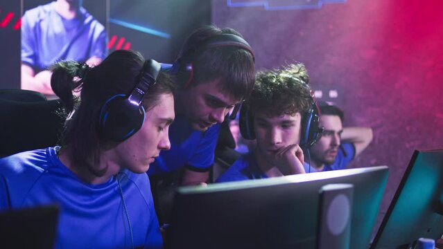 Esportsman gamer in headsets listening to trainer explaining game strategy at start of professional esports competition