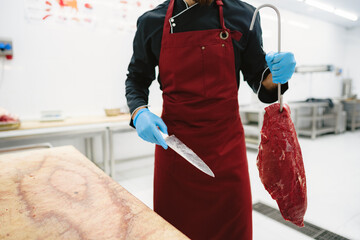 Butcher man holding meat on hook to cut and sell it