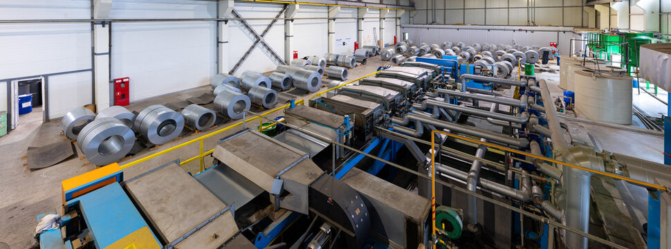 Panoramic photo shot. Steel roofing forming machine. Industrial machine for metal sheet roof coils cut. Process of making steel tile for roof