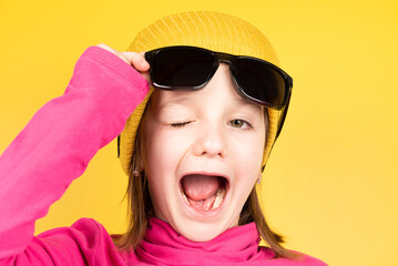 Little girl raising sunglasses and winking eye to camera