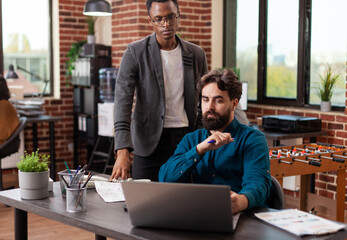 Multiracial businessmen brainstorming ideas for marketing project while working at company strategy in brick wall startup office. Diverse team analyzing statistics planning business collaboration