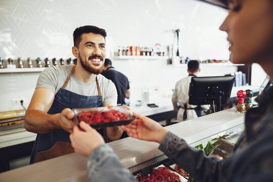 Butcher's shop seller helps to choose product to woman customer