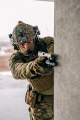 Fototapeta premium Special forces operator wearing Multicam uniform and his handgun xdm 9mm while practicing CQB combat training in the abandoned building. Coyote brown and mc gear with gun in the urban environment.
