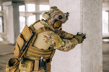 Special forces operator wearing Multicam uniform and his handgun xdm 9mm while practicing CQB combat training in the abandoned building. Coyote brown and mc gear with gun in the urban environment.